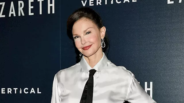 Ashley Judd keeps it business chic in a white satin shirt, black tie, and black trousers at Lazareth...